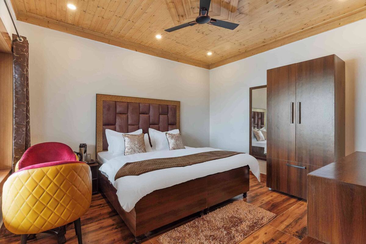 Un dormitorio con techo de madera, una cama con cabecera, un armario y una silla.