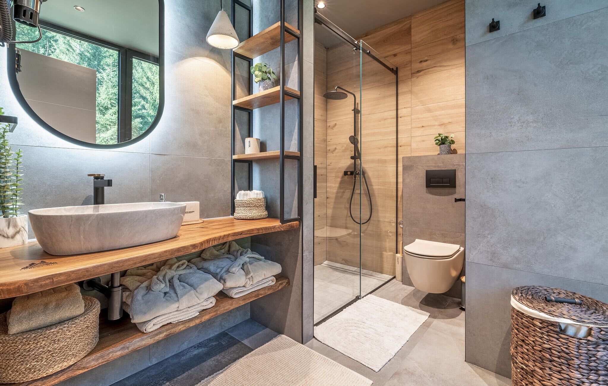 Ein modernes Badezimmer mit einem großzügigen Waschtisch, Holzböden, einer Duschkabine aus Glas und einer Toilette.