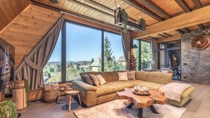 A cozy living room with a large sectional sofa, a wooden coffee table, and a view of the countryside. - Cozy home in Ravna Gora with sauna (Ravna Gora)