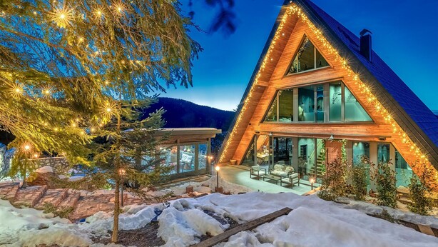 A modern, triangular wooden house with large windows and a glass conservatory, surrounded by snow and a tree. - Cozy home in Ravna Gora with sauna (Ravna Gora)