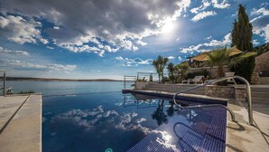 A clear blue infinity pool with a view of the sea and sky.