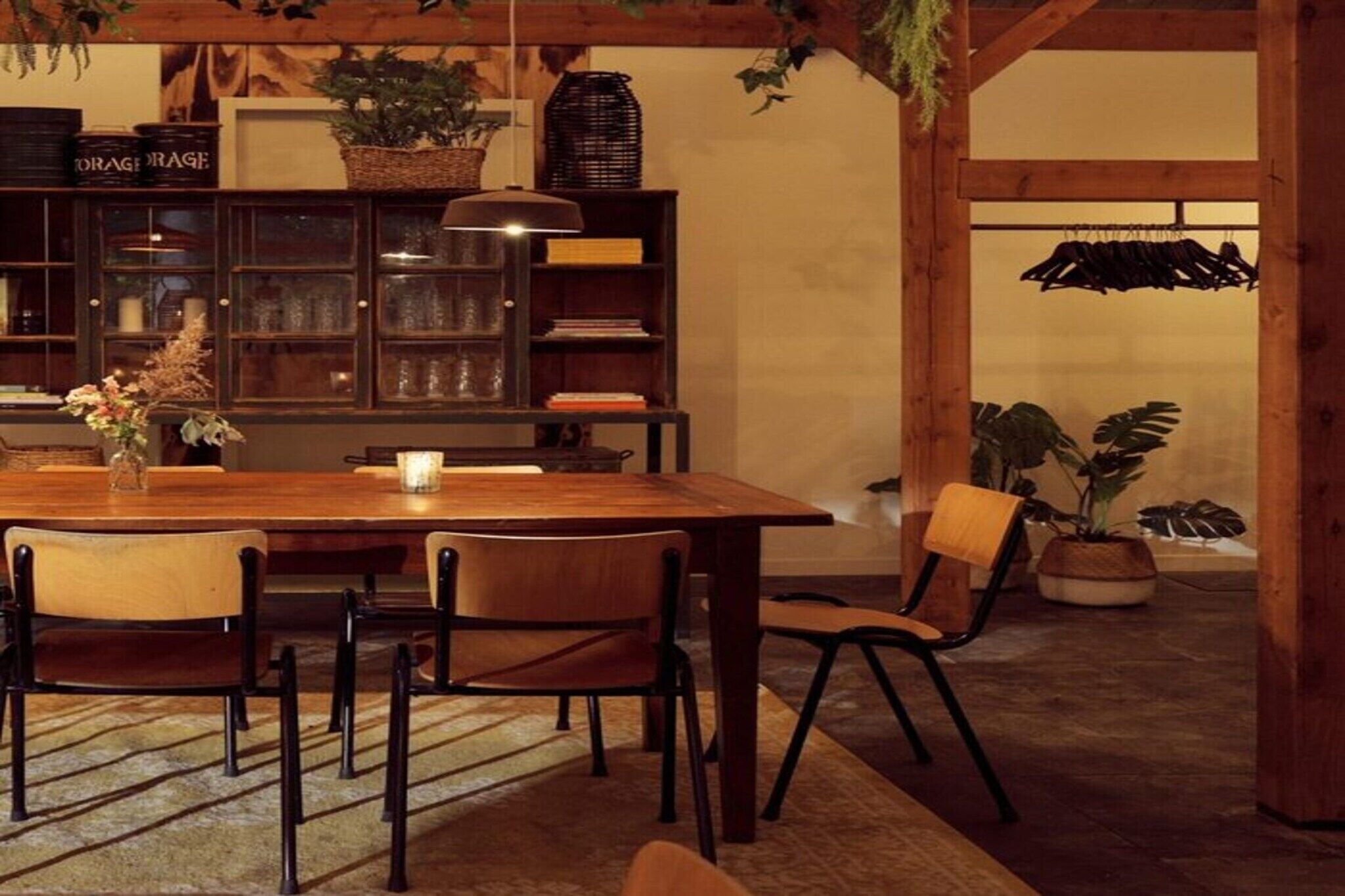 A wooden dining table with chairs, a bookshelf, and potted plants.