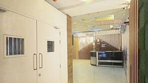 Ett hotellrum med en stor garderob, en glasdörr som leder till en reception och en väl synlig skylt med text.