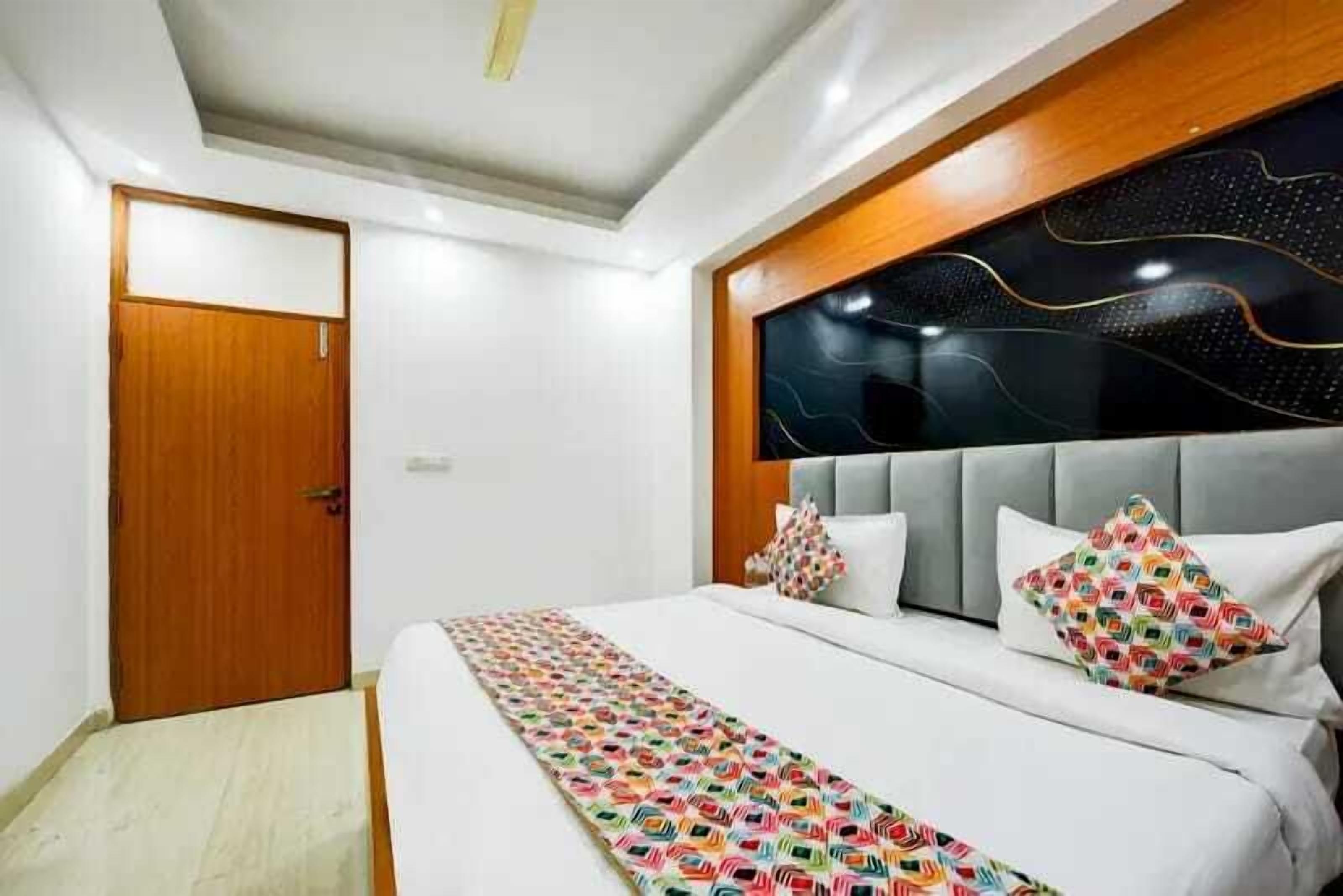 A modern bedroom with a large bed, a wooden door, and a decorative wall panel.