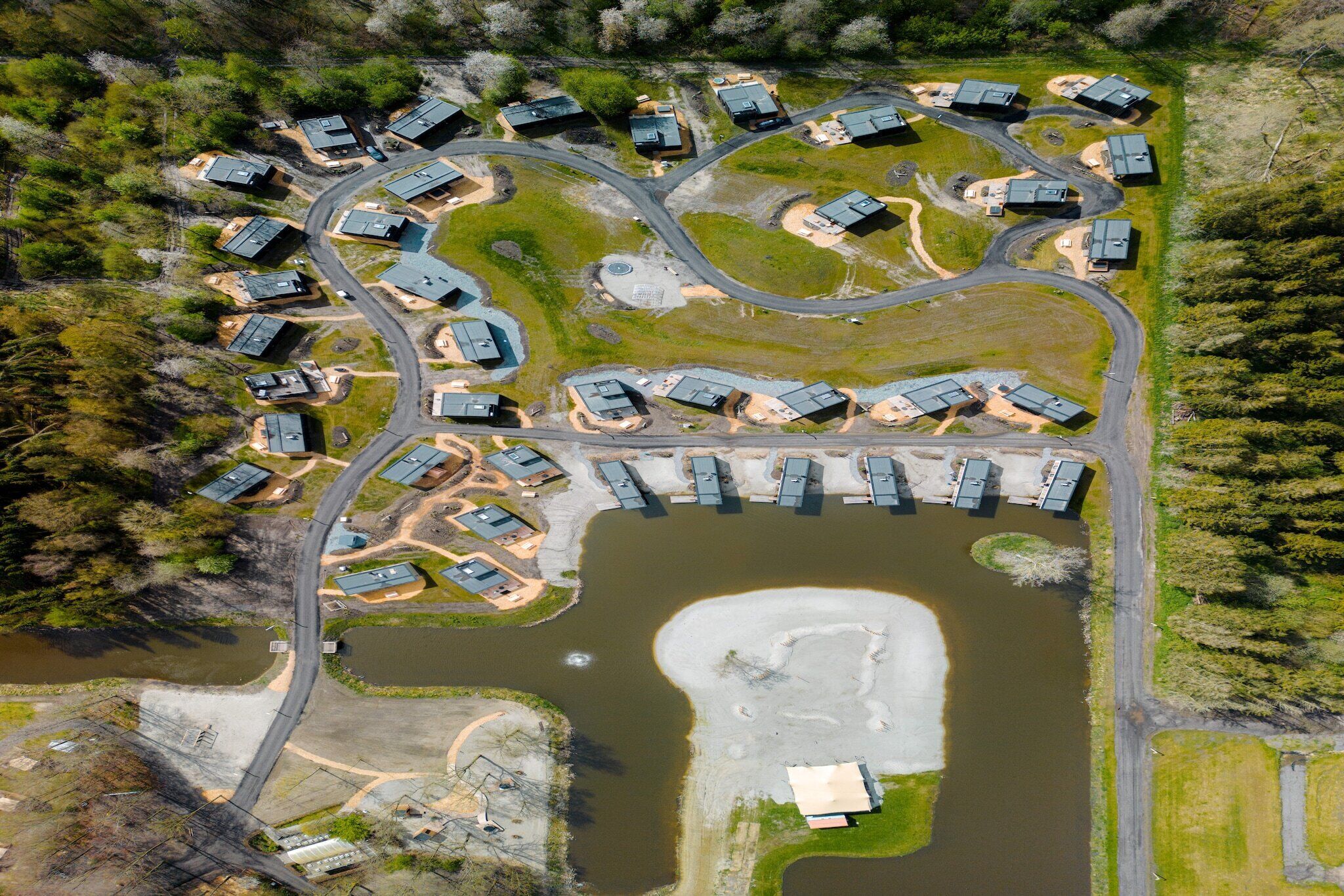 An aerial view of a residential area with multiple houses arranged in a semi-circular pattern around a central water body.