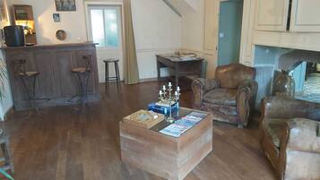 Ein geräumiges Wohnzimmer mit Couchtisch aus Holz, Ledersesseln und einem Kamin.