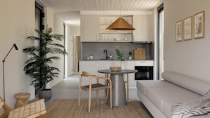 Een moderne keuken met witte kasten, een eettafel met stoelen en een hangende lamp.
