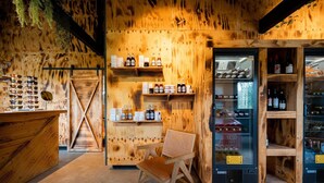 Een houten interieur met planken waarop flessen en glazen staan, een zithoek en een koelvitrine.