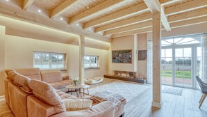 A spacious living room with a large sofa, a fireplace, and a view of a green landscape through large windows. - 3 bedroom stunning home in Sittensen Kalbe (Sittensen Kalbe)
