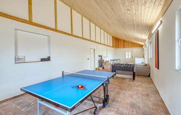 A spacious room with a ping pong table, a foosball table, and a sofa.