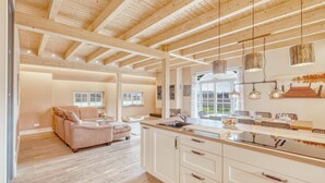 A spacious kitchen with wooden beams, a dining area with a table and chairs, and a large window offering a view of the outdoors. - 3 bedroom stunning home in Sittensen Kalbe (Sittensen Kalbe)