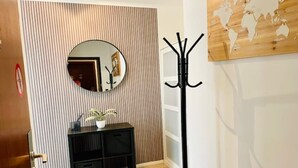 Un couloir avec une console noire, un miroir rond, un porte-manteau et une carte du monde accrochée au mur.
