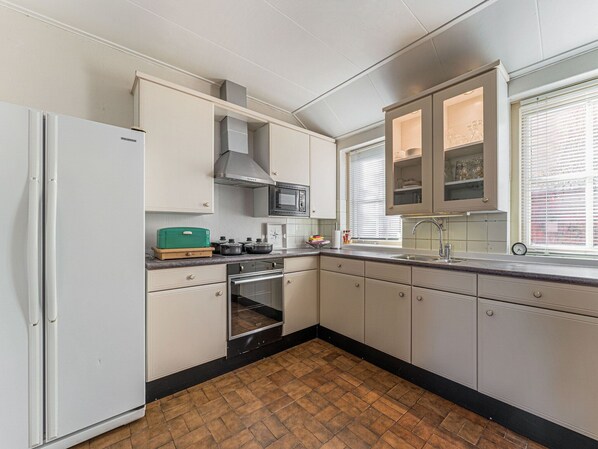 A compact kitchen with white cabinets, a microwave, an oven, and a sink.
