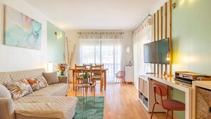 A cozy living room with a sofa, a dining area with a table and chairs, a TV, and a kitchen area with a counter and chairs. - Alba de la Luna Apartment (Albuñol)