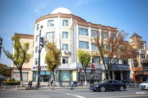 A multi-story building with a rounded corner, storefronts on the ground floor, and a clear sky. - GreenTree Inn Express Hotel (Shanghai Songjiang Sijing Subway Station) (Shanghai)