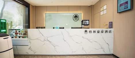 A hotel reception area with a marble counter, a reception desk, and a framed logo on the wall.
