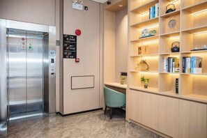 Un ascensor con un panel de control y una pared con un estante que contiene libros y objetos decorativos.
