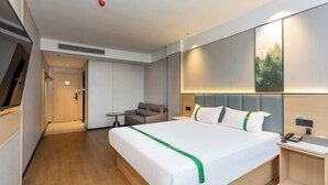 A modern hotel room with a large bed, a desk, a chair, and a painting on the wall. - GreenTree Inn Express Hotel (Shanghai Songjiang Sijing Subway Station) (Shanghai)
