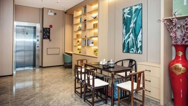 A hotel lobby with a dining area, a reception desk, and a red vase. - GreenTree Inn Express Hotel (Shanghai Songjiang Sijing Subway Station) (Shanghai)