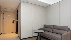 A modern room with a sofa, a small round table, and a door. - GreenTree Inn Express Hotel (Shanghai Songjiang Sijing Subway Station) (Shanghai)