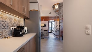A modern kitchen with a built-in stove, a coffee machine, and a toaster. There is a spiral staircase leading to an upper level. - Fortezza Sea Breeze Anne-2BR with view (Rethymno)