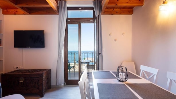 A room with a bed, a television, a wooden ceiling, a balcony with a table and chairs, and a view of the sea. - Fortezza Sea Breeze Anne-2BR with view (Rethymno)
