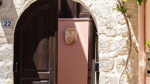 An arched doorway with a dark wooden door, a stone wall, and a potted plant to the right. - Fortezza Sea Breeze Anne-2BR with view (Rethymno)