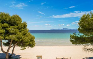 A beach with clear turquoise water, a sandy shore, and a distant mountain range. - Gorgeous home in Alcudia with private swimming pool, can be inside or outside (Alcudia)