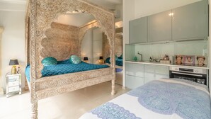 Une chambre à coucher avec un lit à baldaquin, un grand miroir et une petite cuisine moderne.