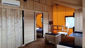 Een houten cabin met een bed, een tafeltje, een wastafel en een airconditioning.