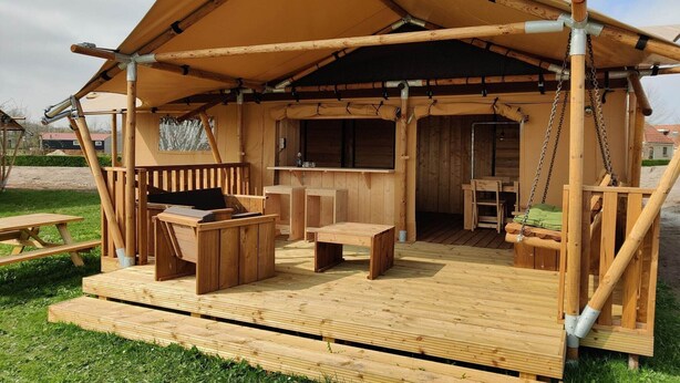 Een houten buitenconstructie met een overdekte zithoek, een tafel en een bank.
