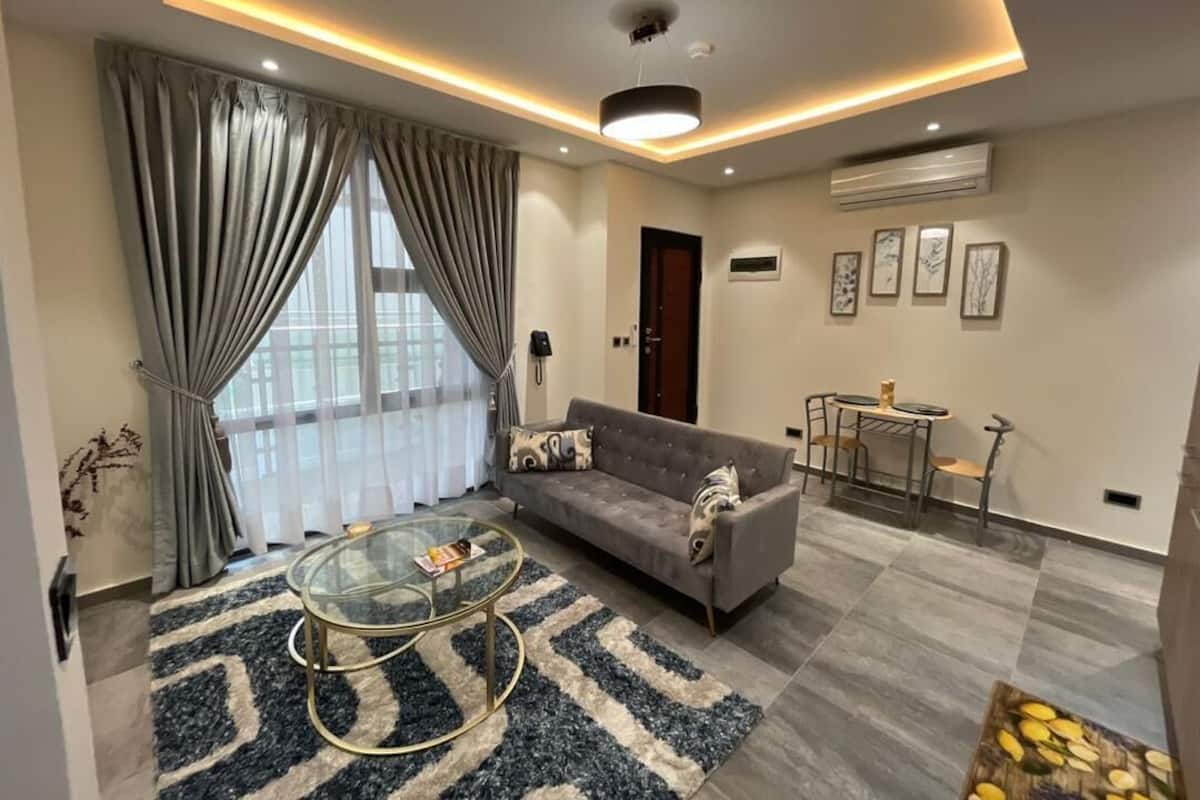 A modern living room with a sofa, coffee table, and a dining area with chairs.