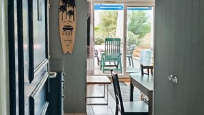Un pasillo que conduce a un área de comedor con una decoración de tabla de surf, una silla verde y una mesa.