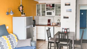 Un espacio habitable compacto con kitchenette, zona de comedor y cama.