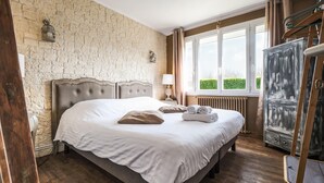Ein Schlafzimmer mit einem großen Bett, einem Heizkörper, einem Fenster mit Vorhängen und einem Holzkleiderschrank.