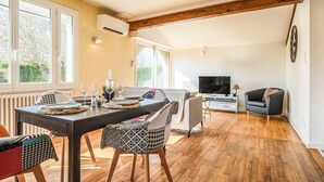 Ein Essbereich mit einem Tisch für vier Personen, einer Couch, einem Fernseher und einem Kamin.
