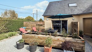 Ein Haus mit überdachter Terrasse, Gartenmöbeln und Pflanzkübeln.