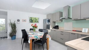 Una cocina moderna con armarios grises, una mesa de comedor con sillas, un microondas y un horno.