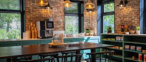 A restaurant interior with a brick wall, hanging pendant lights, a coffee machine, and a counter with stools.