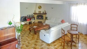 A living room with a sofa, a wooden coffee table, a fireplace, and a dining area with a table and chairs. - Stunning home in Vedène (Vedène)