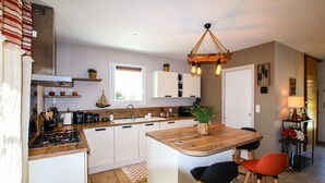 A modern kitchen with white cabinets, a wooden island, and a hanging light fixture. - Villa contemporaine Provençale (Mormoiron)