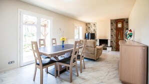Ein Essbereich mit Holztisch und Stühlen, einem Sofa, einem Kamin und einer Wanduhr.