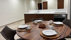 A modern kitchen with a dining table set for four, equipped with a sink, stove, and oven. - Modern studio in a beachfront building (Cozumel)