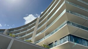 A modern multi-story building with a curved facade and large windows. - Modern studio in a beachfront building (Cozumel)