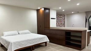A bedroom with a bed, a wooden wardrobe, and a built-in desk with a mirror. - Modern studio in a beachfront building (Cozumel)