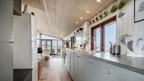 Een moderne keuken met een houten plafond, grote ramen en uitzicht op het platteland.