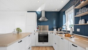 A modern kitchen with white cabinets, a Bosch oven, a stainless steel range hood, and a wooden countertop. - 3 bedroom nice home in Middelfart (Middelfart)