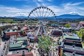 A Ferris wheel in a town square with surrounding buildings and a mountain backdrop. - Lovely Cabin near GSMNP & Attractions (Gatlinburg)