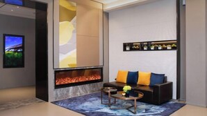 Ein modernes Wohnzimmer mit Kamin, einer Couch mit bunten Kissen, einem Couchtisch und einem an der Wand befestigten Fernseher.