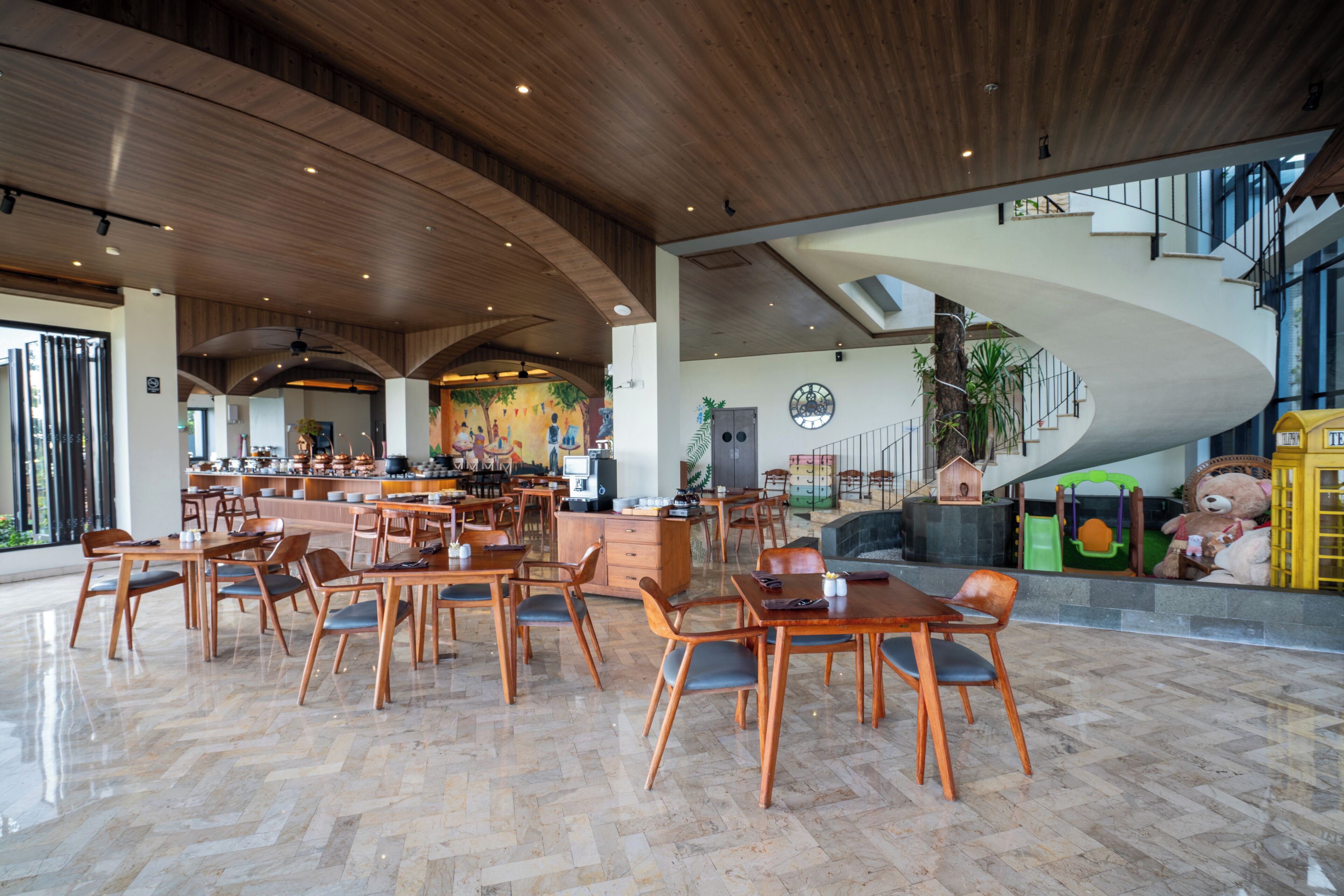 A spacious lobby with wooden flooring and a curved staircase.